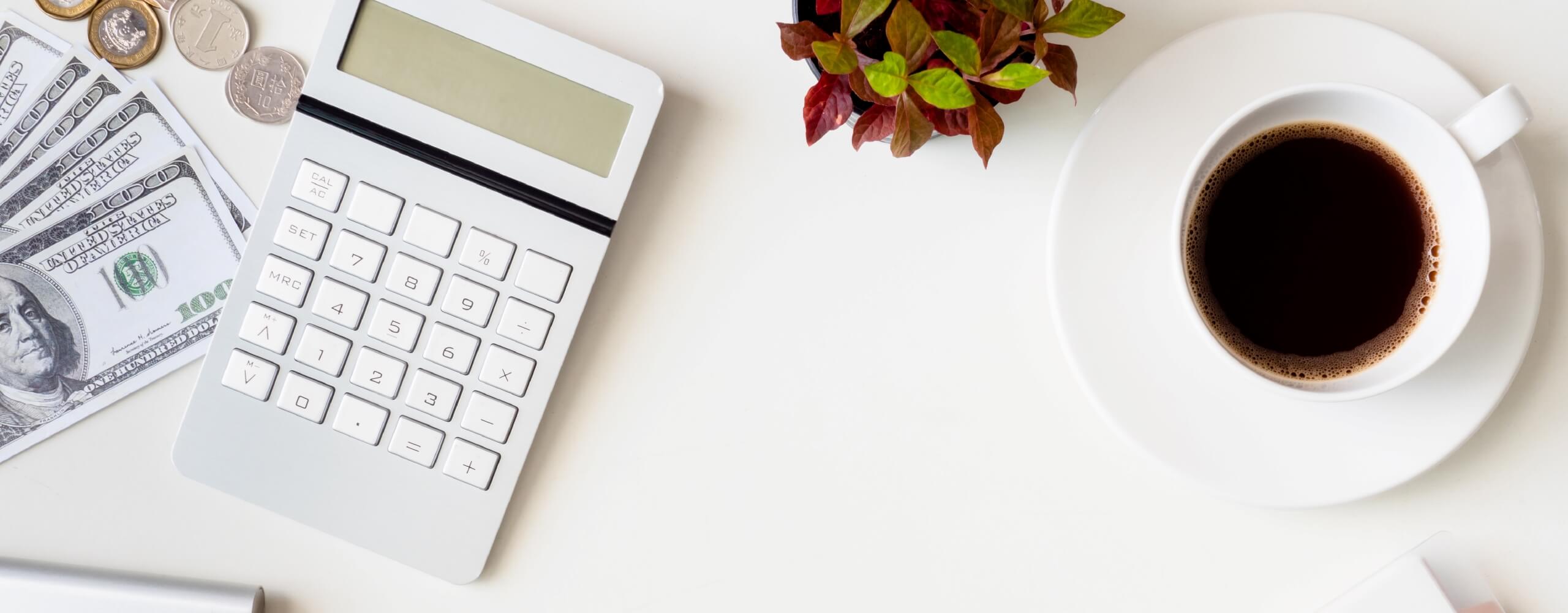 Tabletop with a house plant, cup of coffee, dollar bills, and coins.
