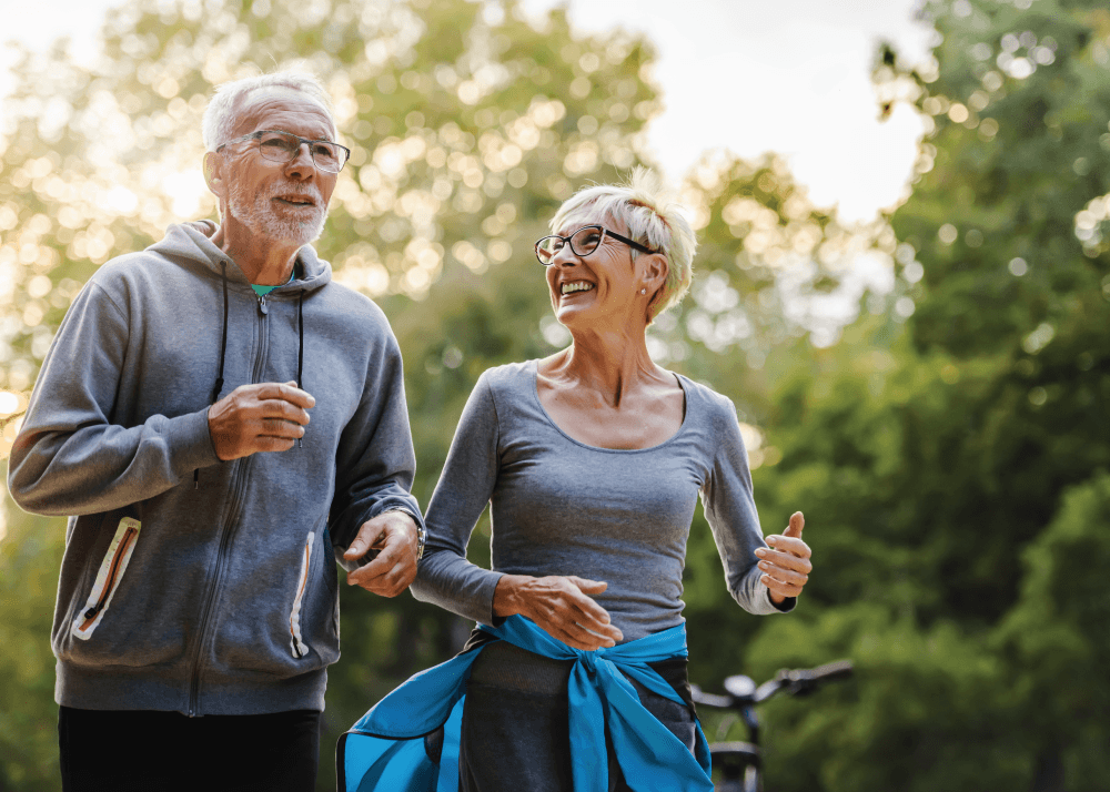 A couple of people jogging in a park alongside each other.